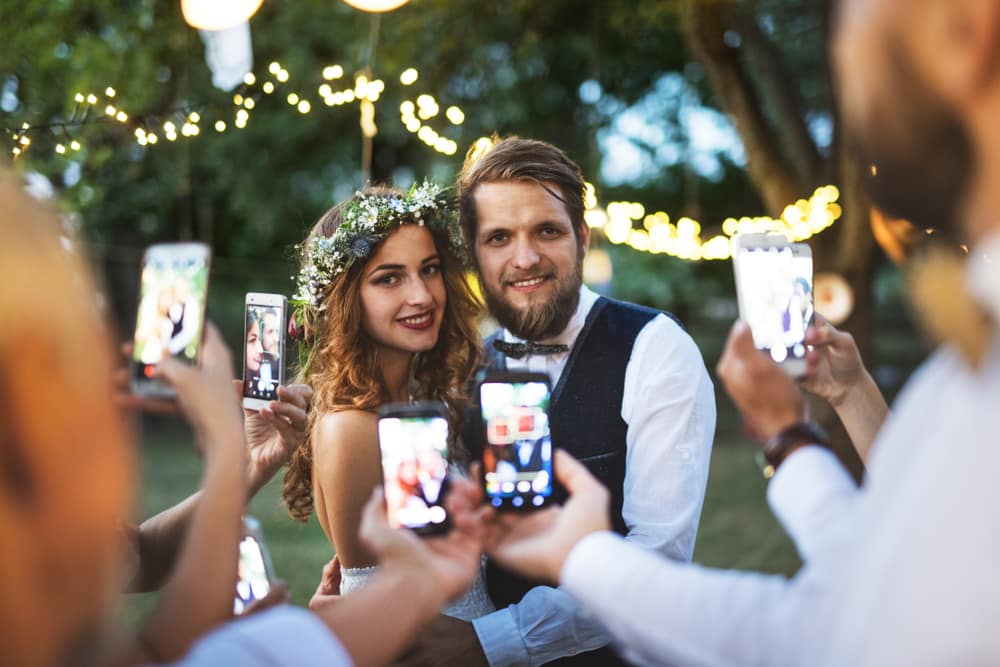 Wedding couple being photographed with a smartphone at their celebration