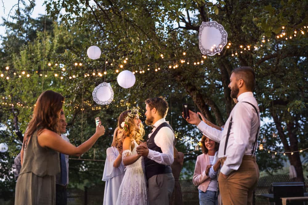 Guests laughing and taking photos at an outdoor party